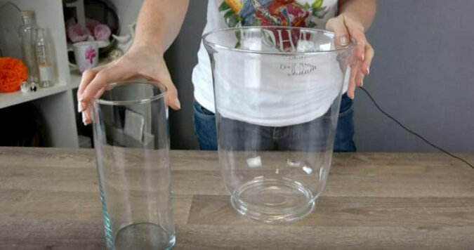 Kobieta wkłada świeczkę do szklanego wazonu i zalewa wszystko wodą