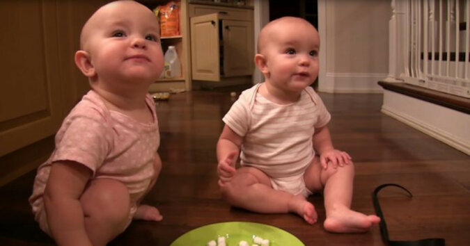 Urocze bliźniaczki, które się cieszą z wielkiego talerza pianek marshmallows